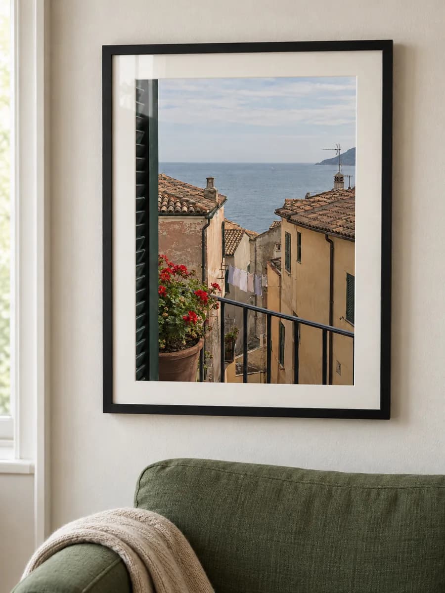 The same coastal photo in a black frame above an olive armchair