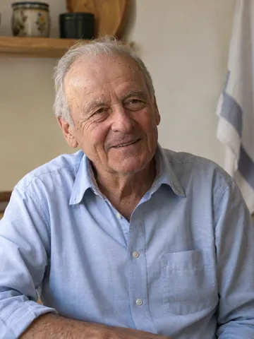 Smiling grandfather in a pale blue shirt at a kitchen table